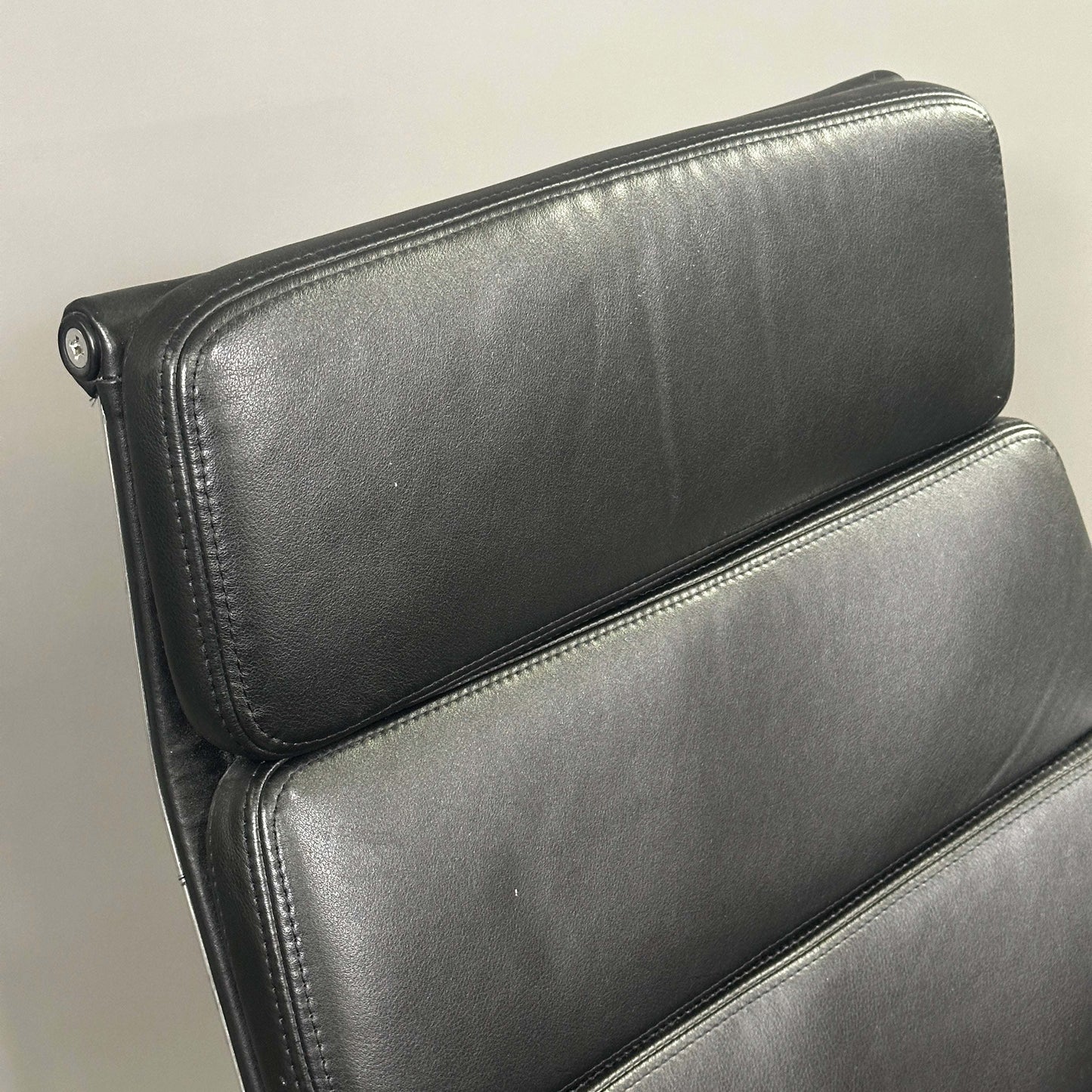 Close-up of black leather soft pad on Vitra EA 216 Eames Alu swivel chair backrest