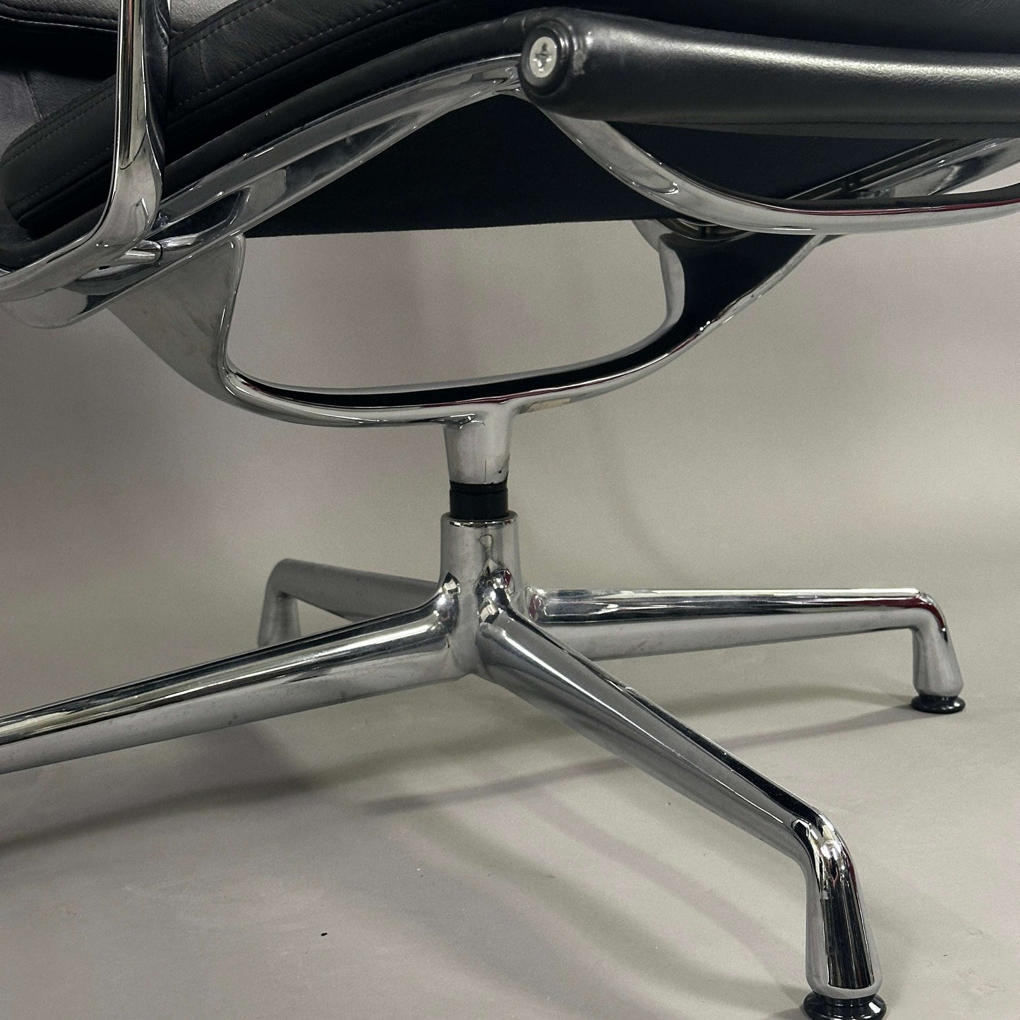 Close-up of the chrome swivel base of Vitra EA 216 office chair with black soft pad leather upholstery