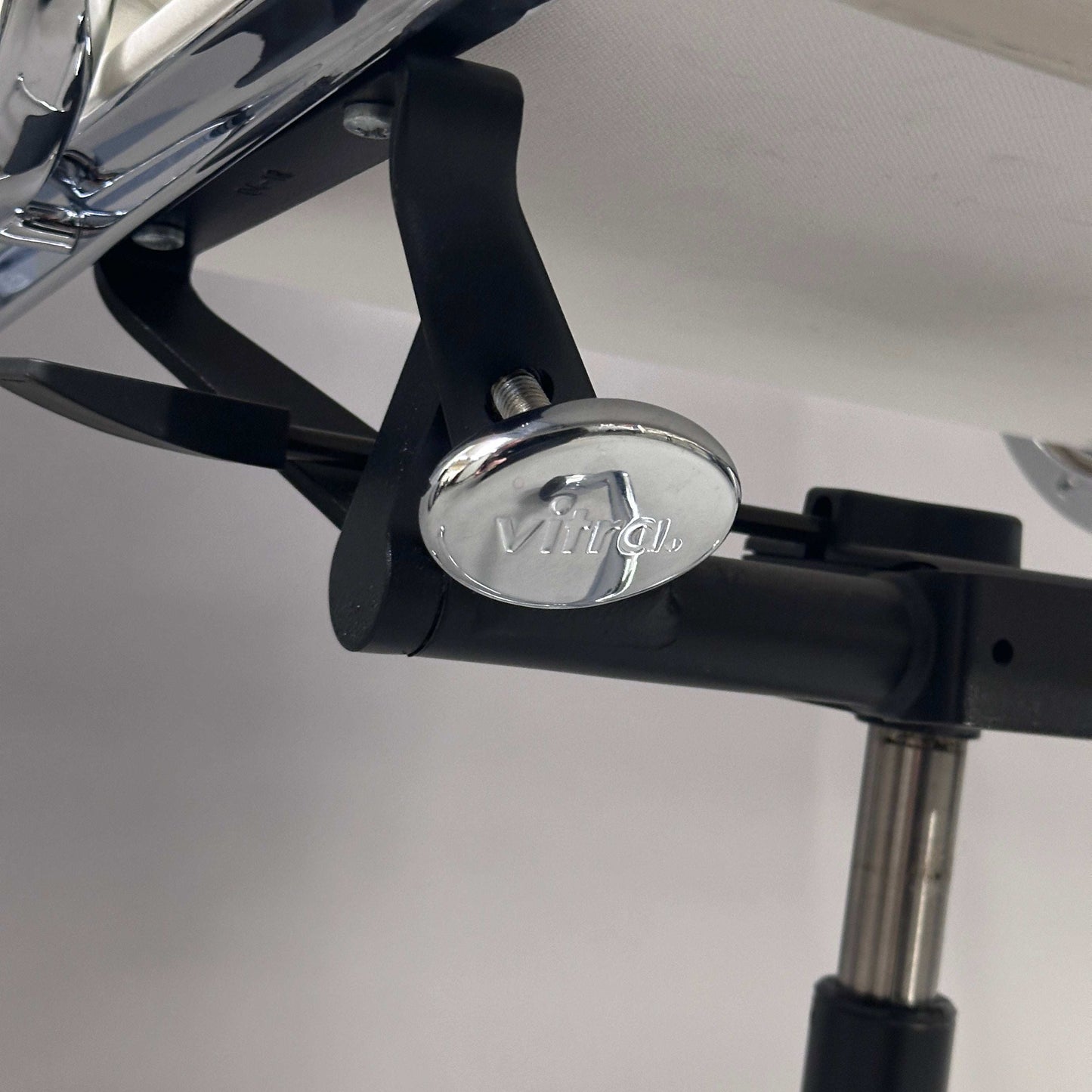 Detailaufnahme des Vitra EA 217 Bürostuhls mit weißem Lederbezug und Chromgestell, verstellbare Sitzhöhe und Drehfunktion.