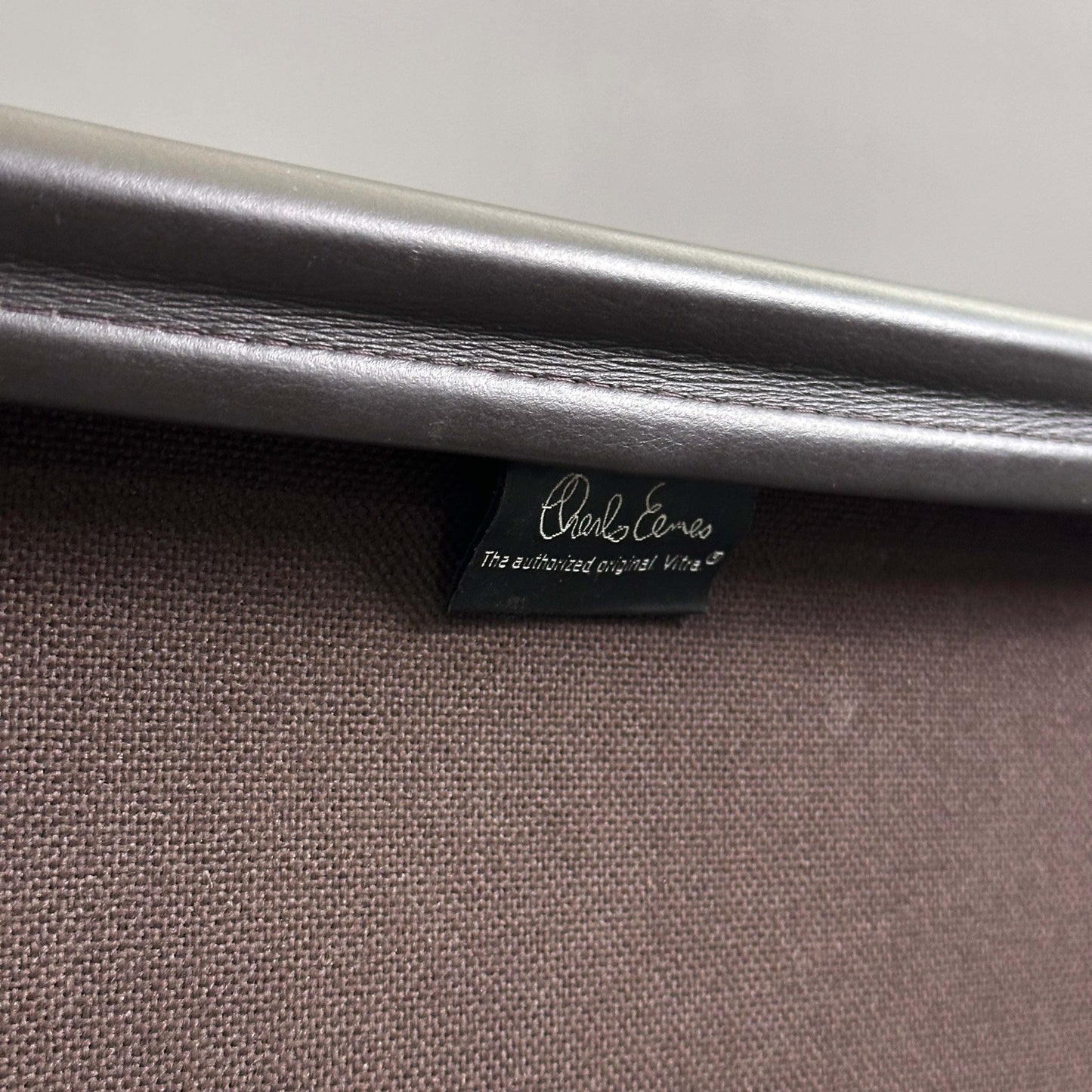 Vitra EA 219 Eames Alu Chair mit dunkelbraunem Lederbezug und chromfarbenem Gestell, Nahaufnahme des Labels
