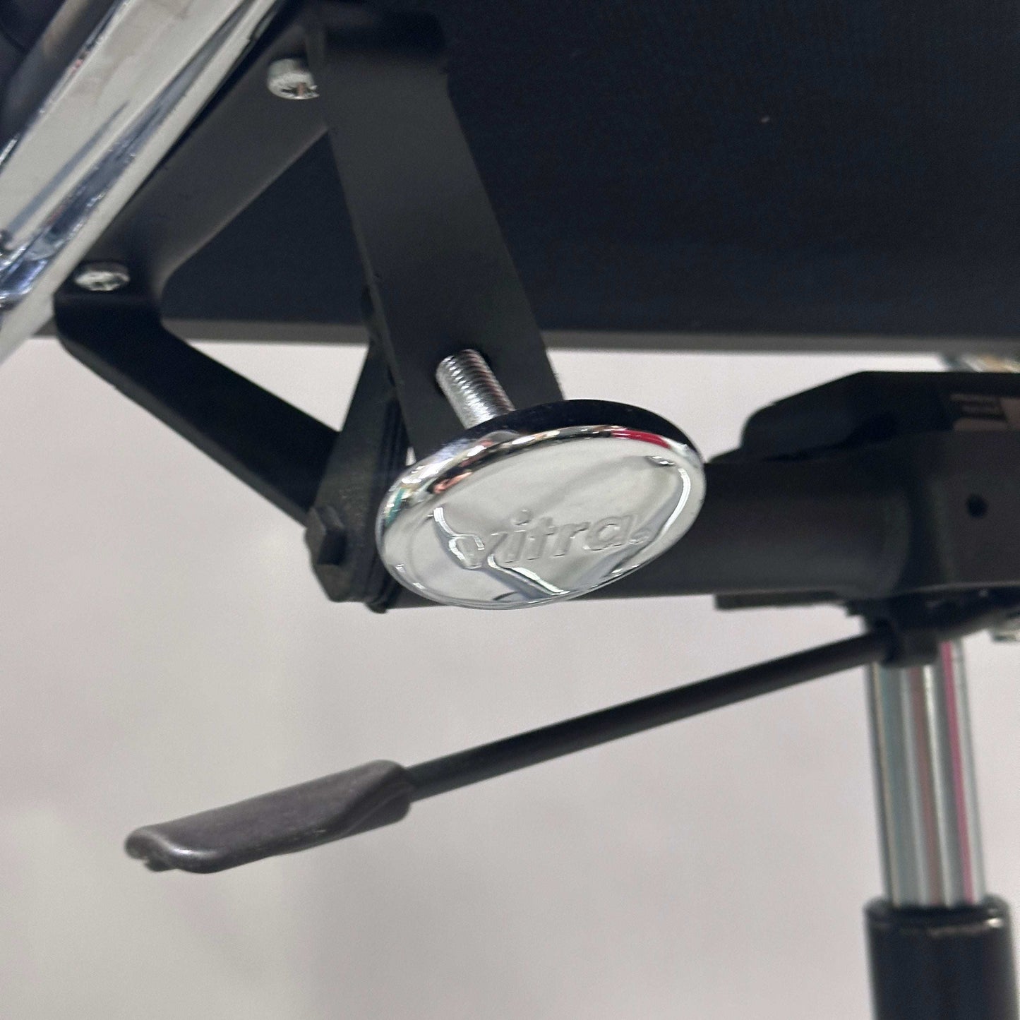 Detailaufnahme des verchromten Mechanikteils mit Vitra-Logo am Vitra EA 219 Bürostuhl aus schwarzem Leder