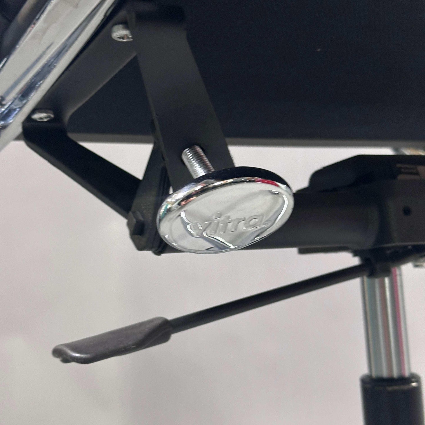 Detailaufnahme des verchromten Mechanikteils mit Vitra-Logo am Vitra EA 219 Bürostuhl aus schwarzem Leder