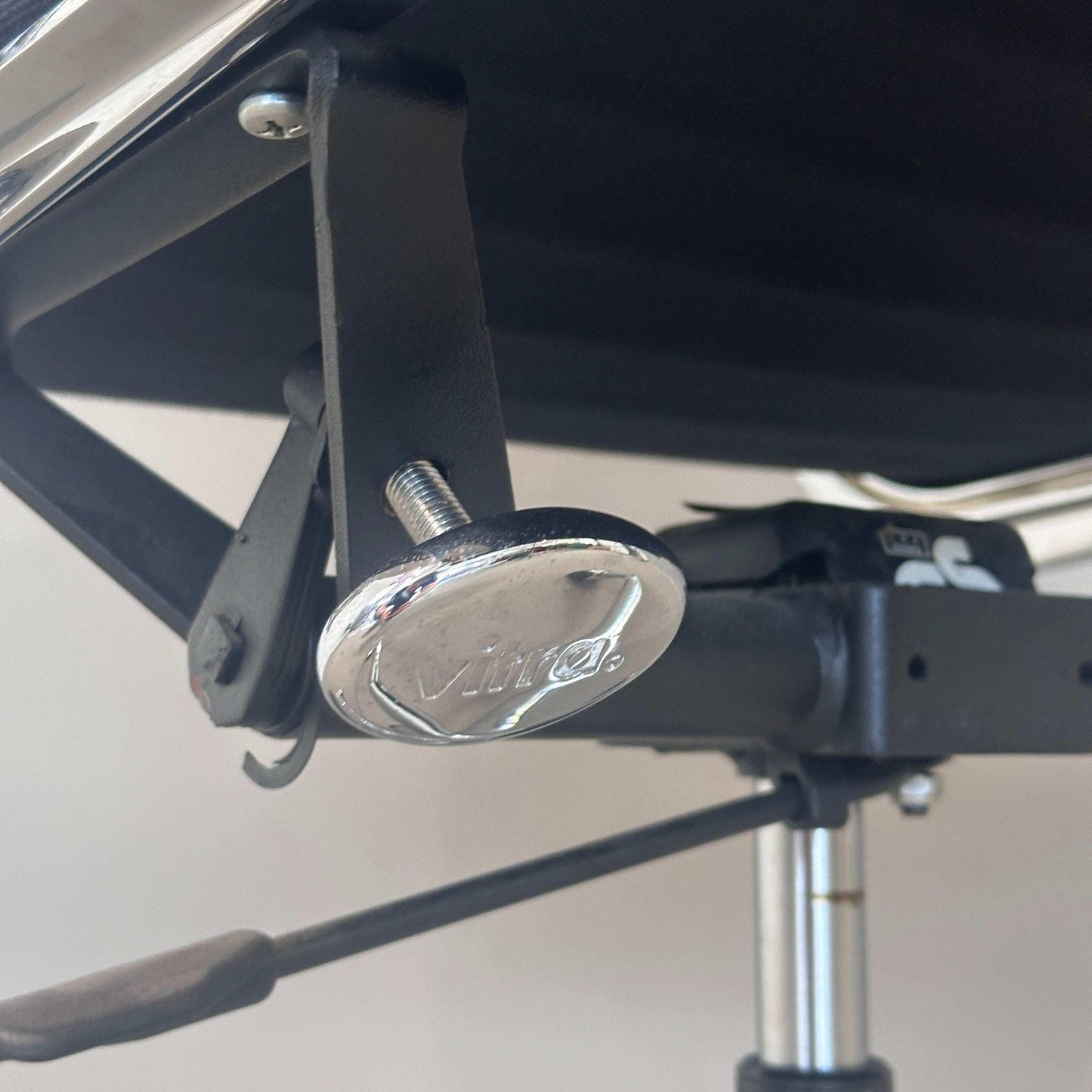Detailaufnahme der verchromten Einstellschraube am Vitra EA 219 Bürostuhl mit schwarzem Stoffbezug