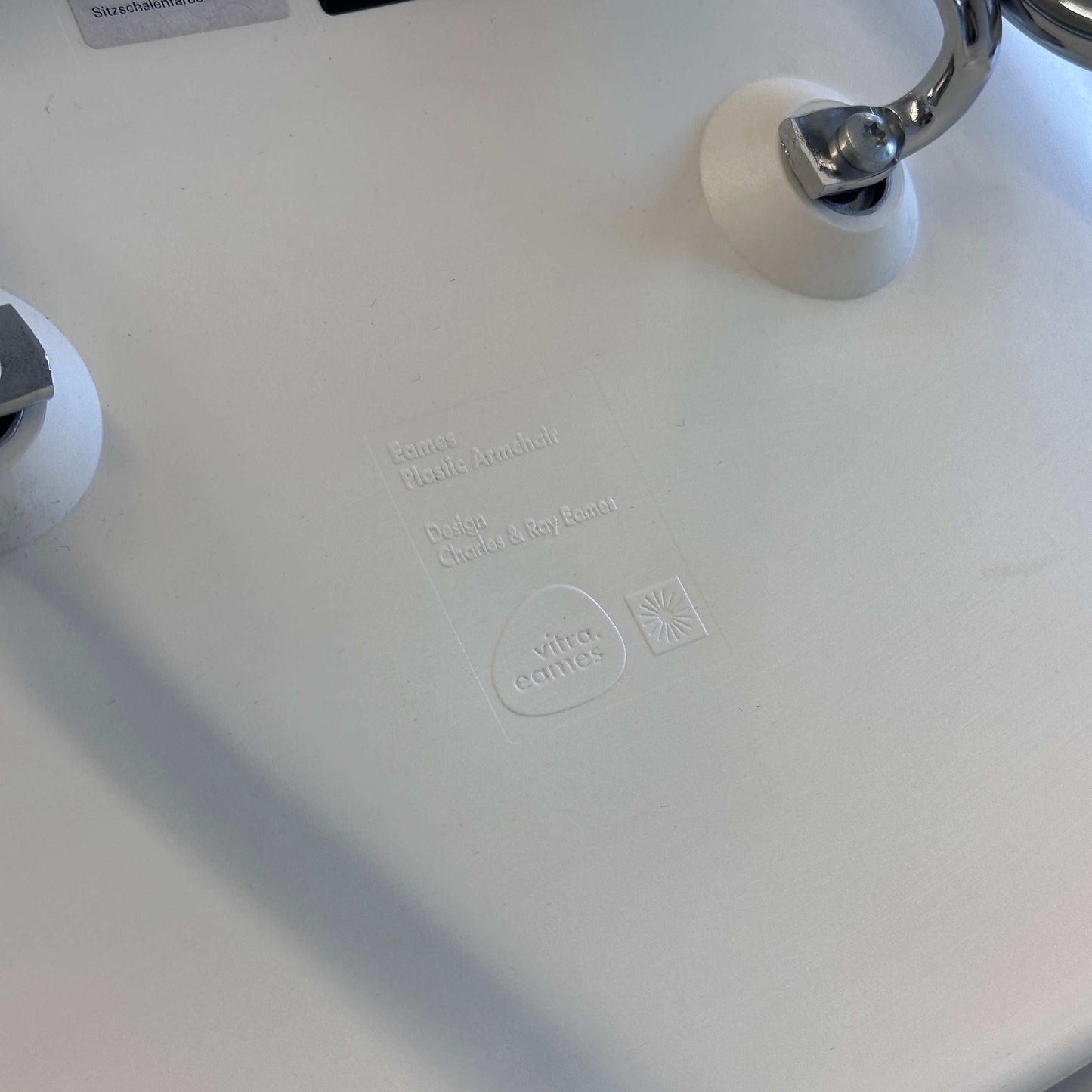 Vitra Eames Plastic Armchair Sitzschale PE weiß mit verchromtem Metallgestell Nahaufnahme Logo und Designprägung