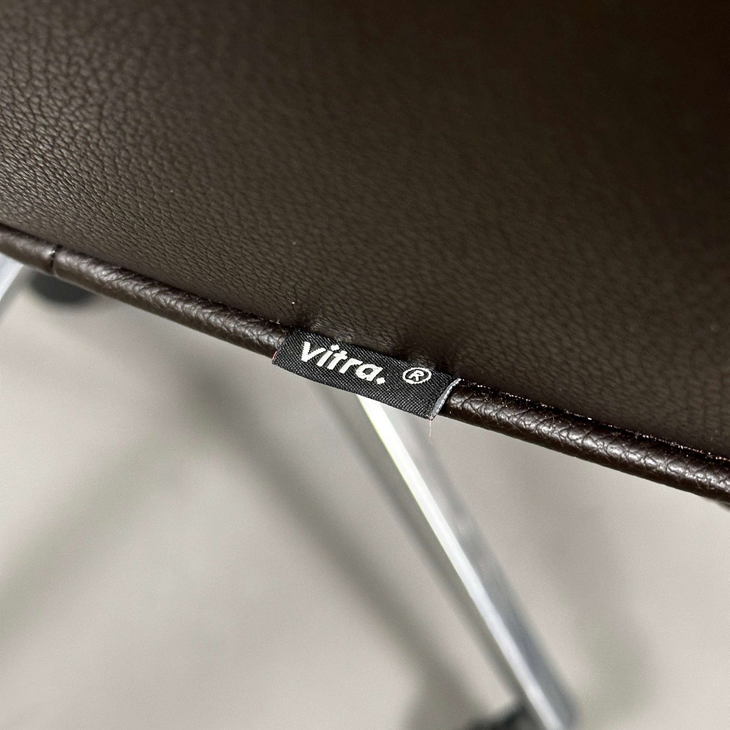 Nahaufnahme des braunen Lederbezugs am Vitra Grand Executive Highback Chefsessel mit Vitra-Logo am Sitzrand