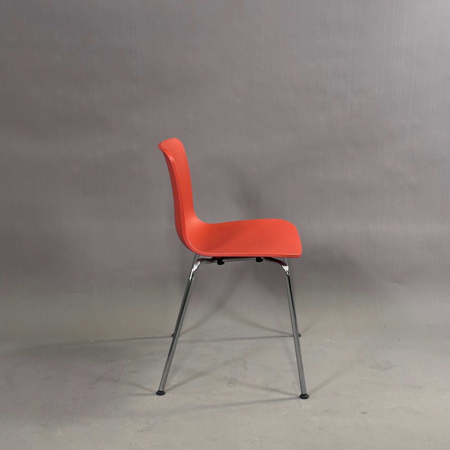 Vitra HAL Schalenstuhl mit roter Kunststoffschale und verchromtem Metallgestell, Seitenansicht vor neutralem Hintergrund