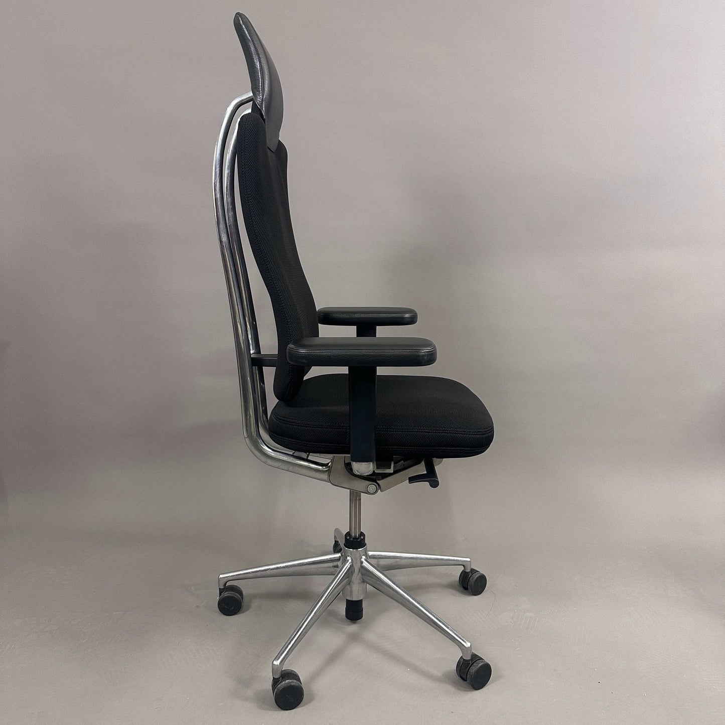 Black Vitra Headline office chair with fabric seat, leather headrest, adjustable armrests, and chrome base with wheels