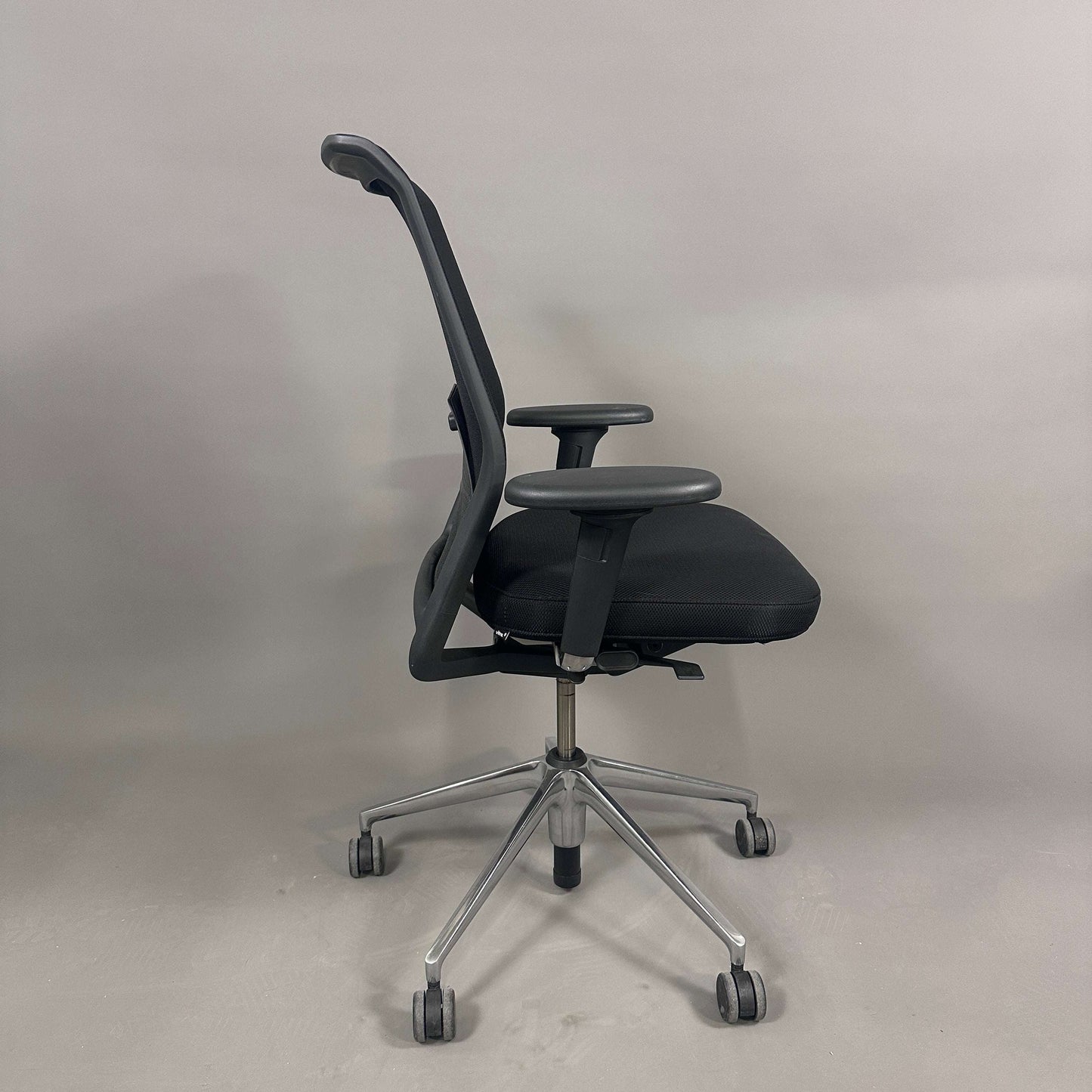Schwarzer Vitra ID Mesh Bürostuhl mit verstellbarer Sitzhöhe, Sitztiefe, Lordosenstütze und Armlehnen auf chromfarbenem Alu-Gestell.