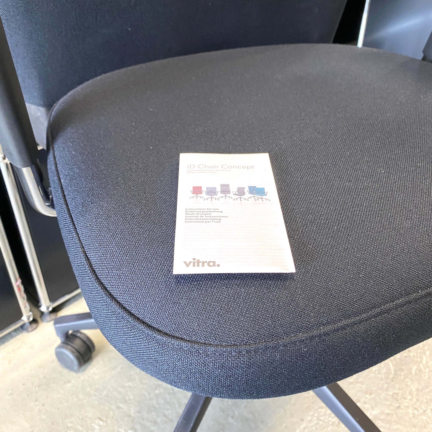 Close-up of black fabric seat of Vitra ID Trim L office chair with adjustable ergonomic features and black leather headrest