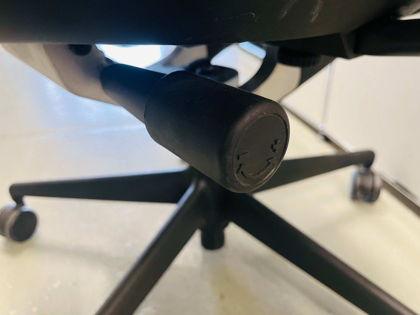 Close-up of the black adjustment lever and base of the Vitra Meda Pro office chair with a breathable mesh backrest and ergonomic features.