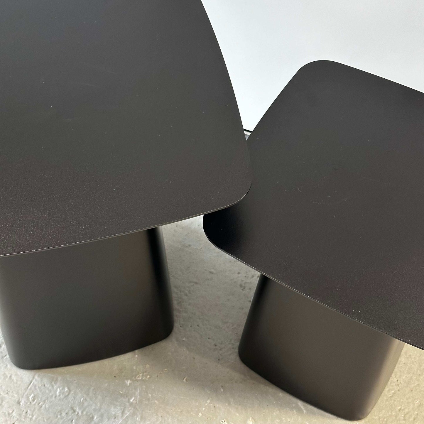 Two matte black Vitra Metal Side Tables in sizes M and S with rounded edges and sleek metal design on a light floor.
