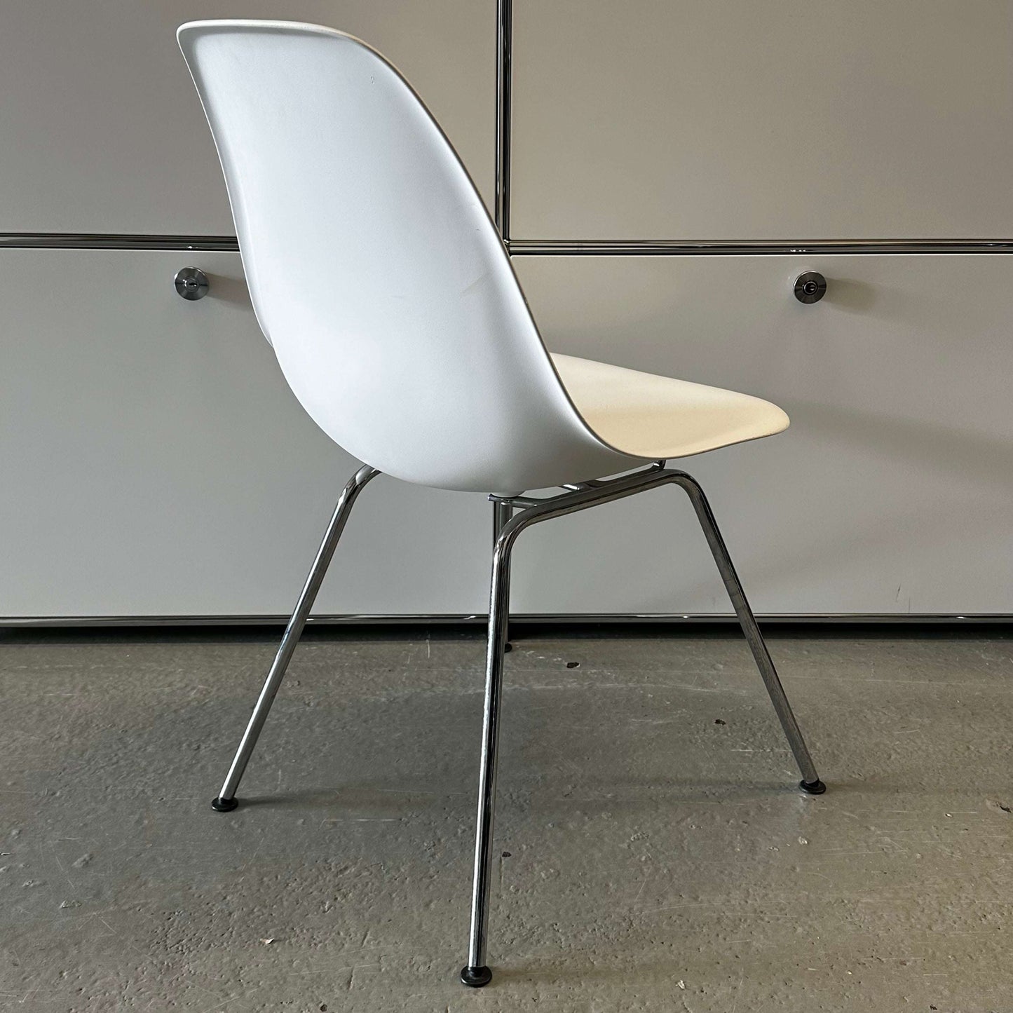 White Vitra Plastic Side Chair with chrome legs and minimalist design in a modern indoor setting