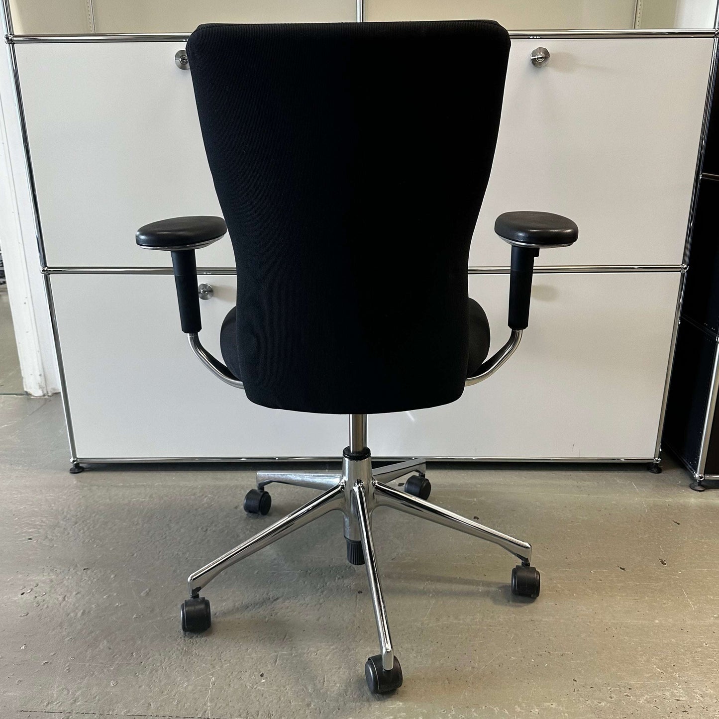 Black Vitra T-Chair office chair with adjustable armrests and chrome base on casters viewed from the back