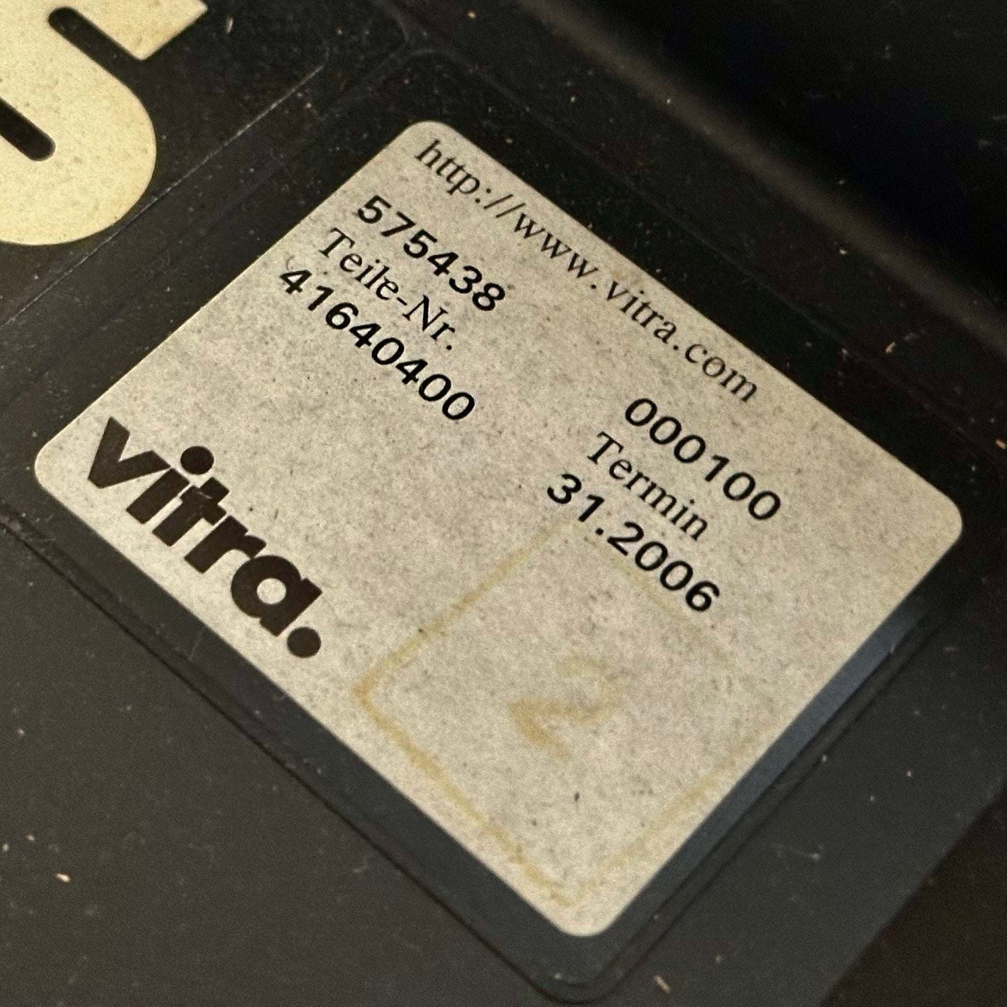 Close-up of a Vitra T-Chair black label with product number and date details