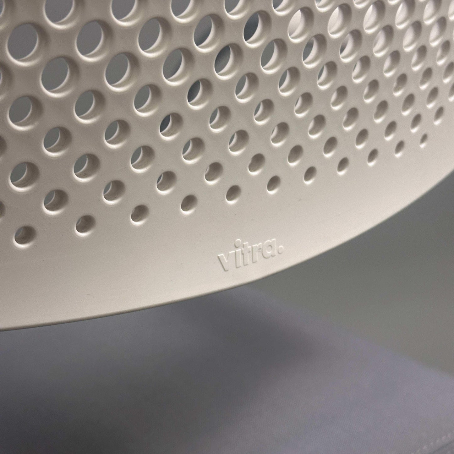 Close-up of white perforated plastic backrest with Vitra logo on Vitra Visavis 2 chair
