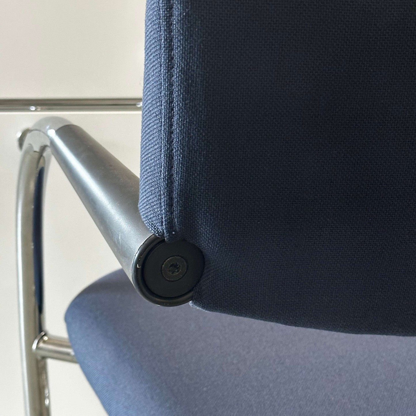 Close-up of blue Vitra Visavis office chair with padded softback and chrome armrest