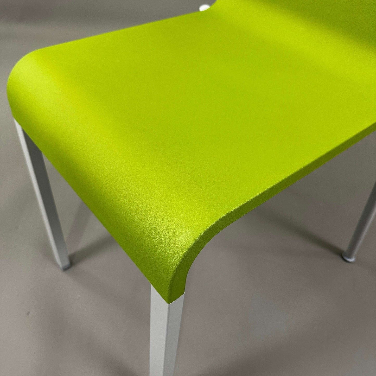 Close-up of Vitra .03 Besucherstuhl avocado green plastic seat with matte silver aluminum frame, stackable visitor chair.
