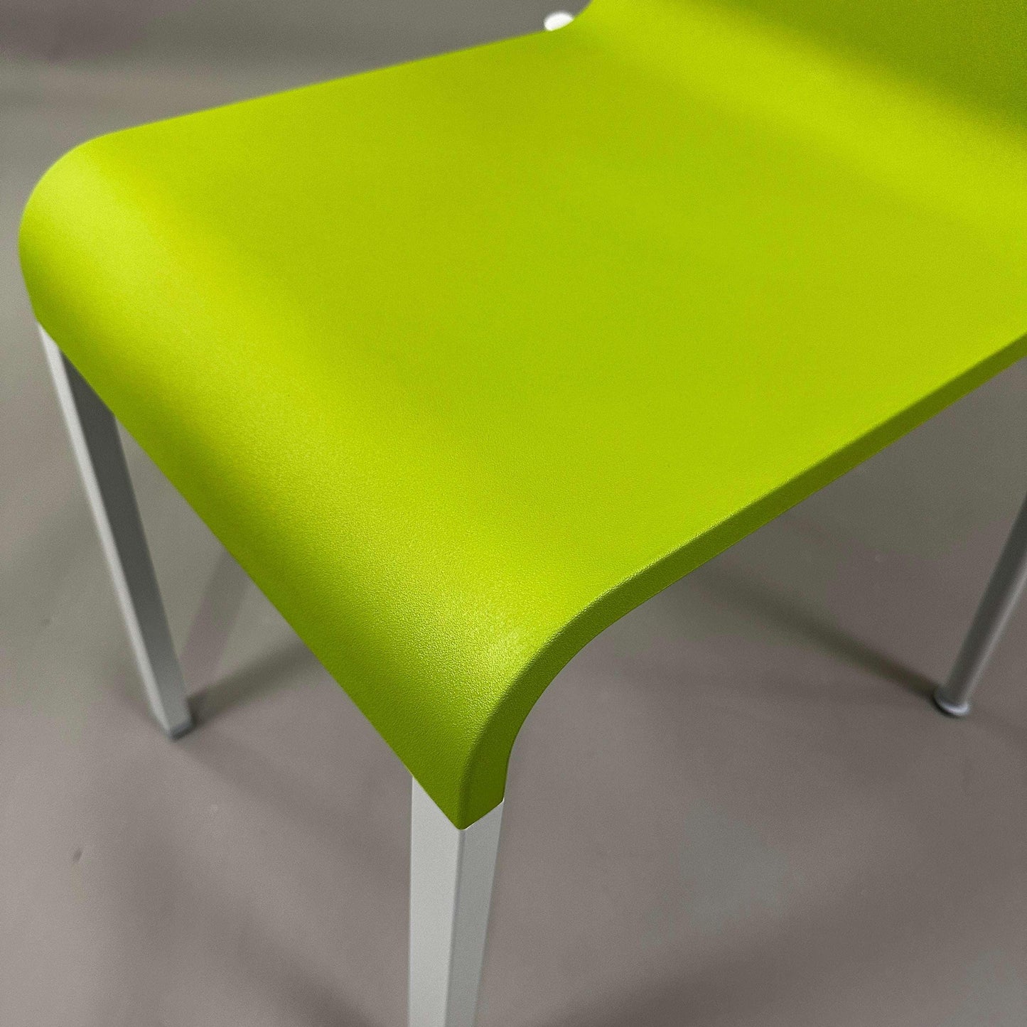 Close-up of Vitra .03 Besucherstuhl avocado green plastic seat with matte silver aluminum frame, stackable visitor chair.