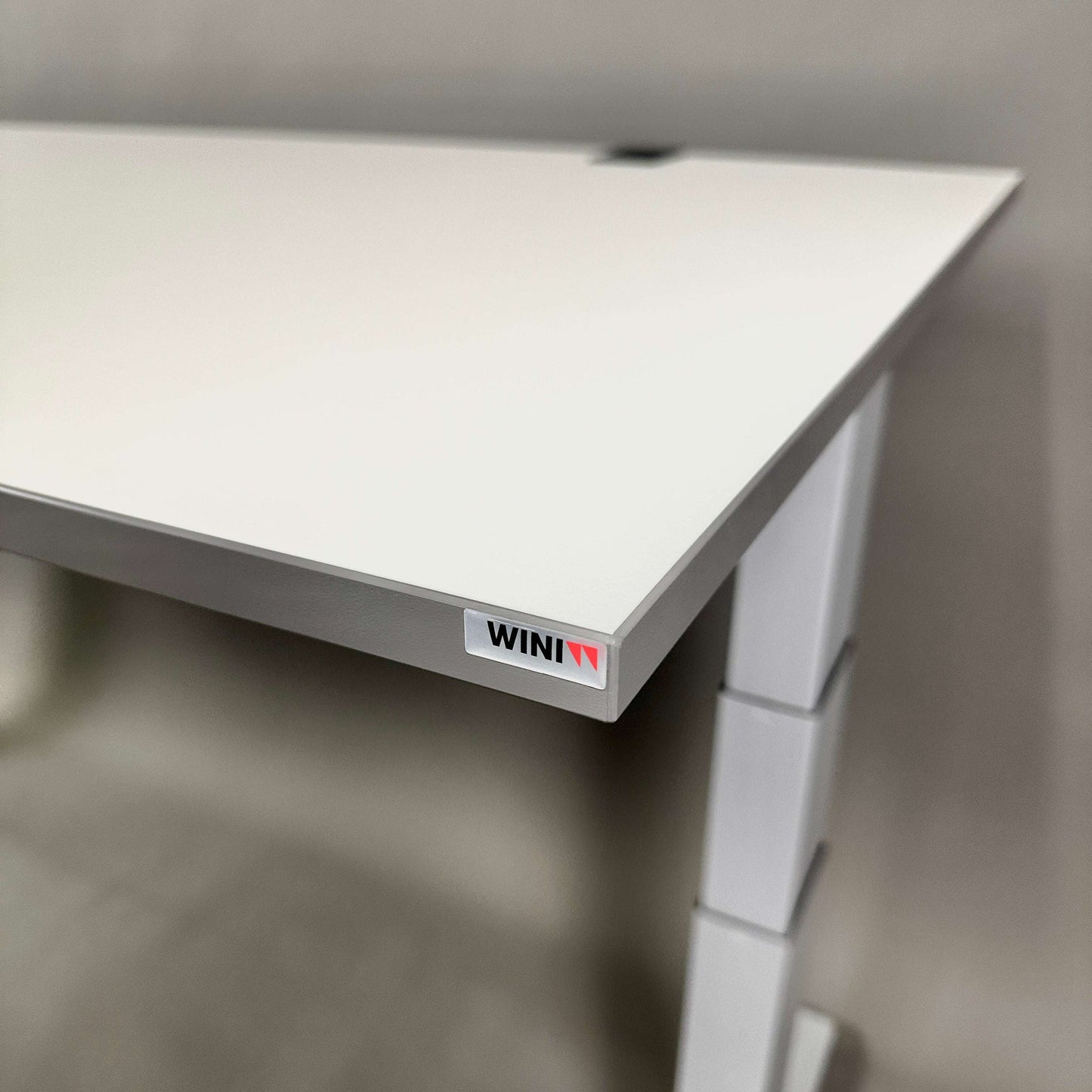 Close-up of white WINI Flow Schreibtisch electric height-adjustable desk corner with logo