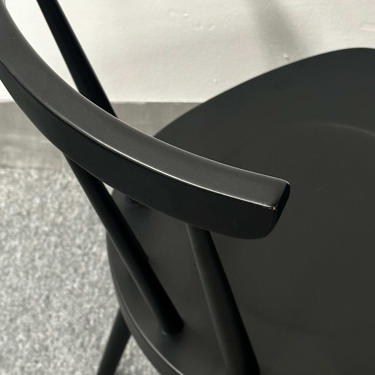 Close-up of the black Wagner W-1960 Chairity chair showcasing its curved armrest and minimalist design.