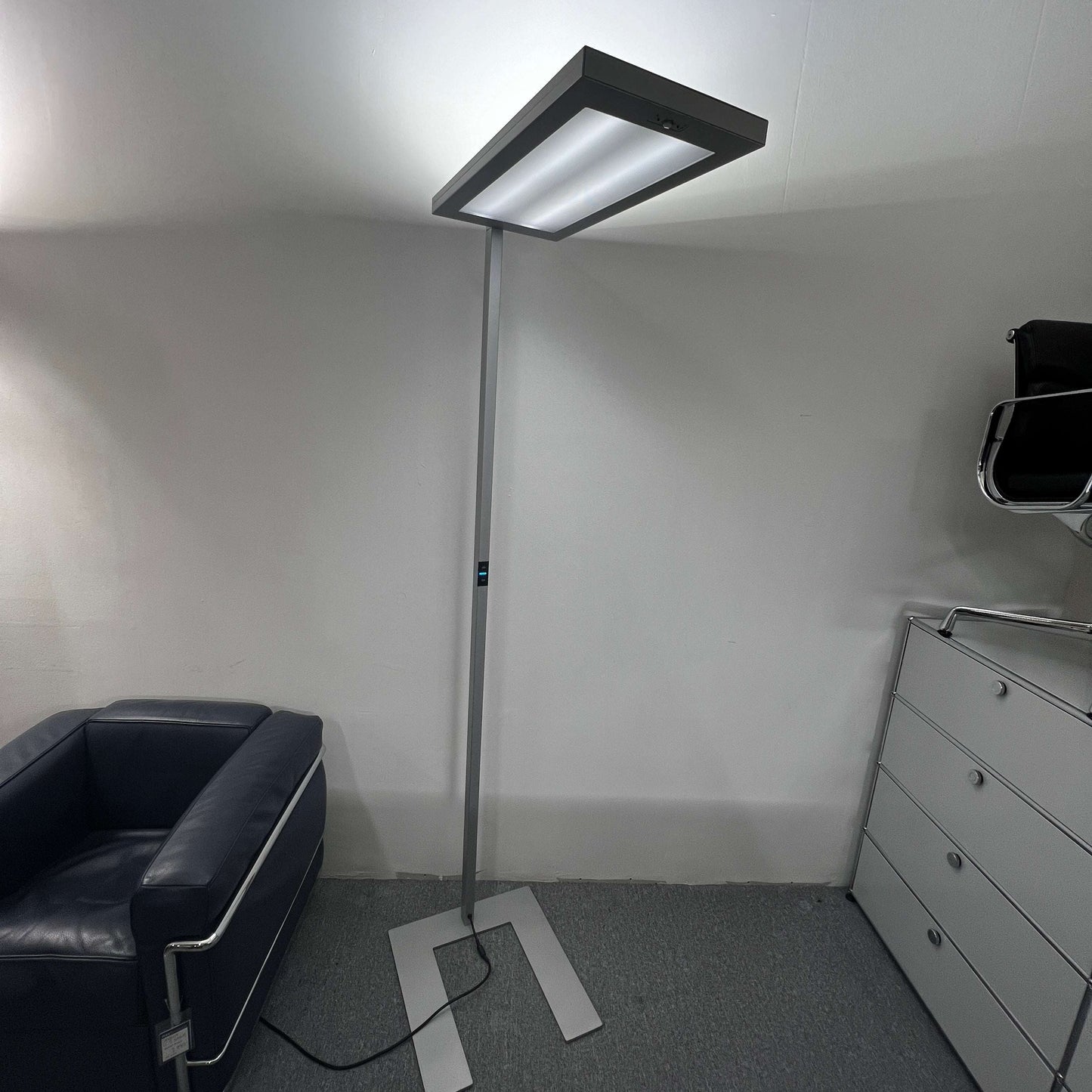 Waldmann Lavigo LED silver floor lamp with integrated motion and daylight sensor in modern office setting