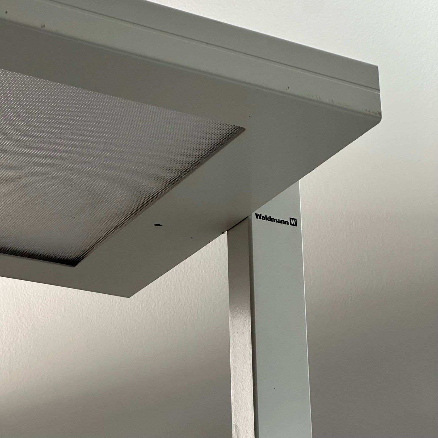 Close-up of white Waldmann Lavigo LED floor lamp with integrated motion and daylight sensor.