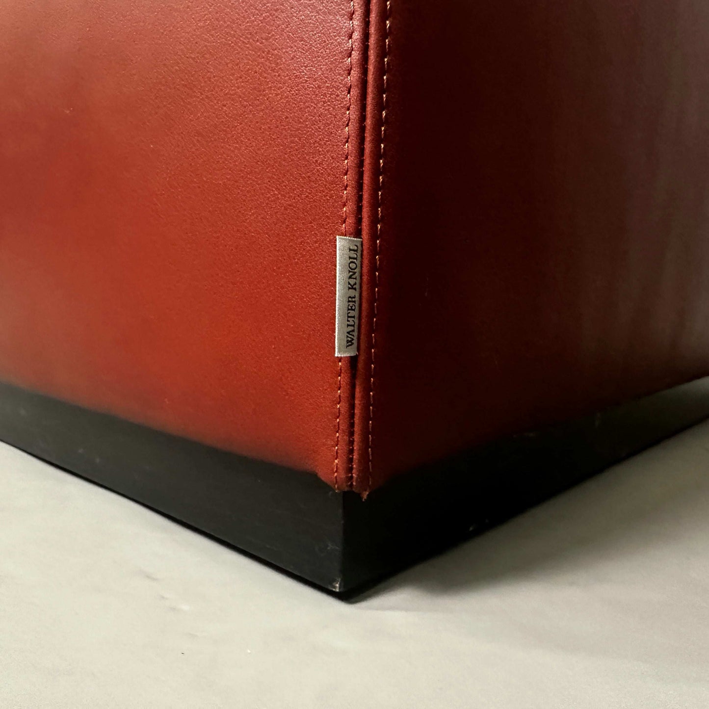 Close-up of dark red leather corner with Walter Knoll label on Foster 500 armchair base