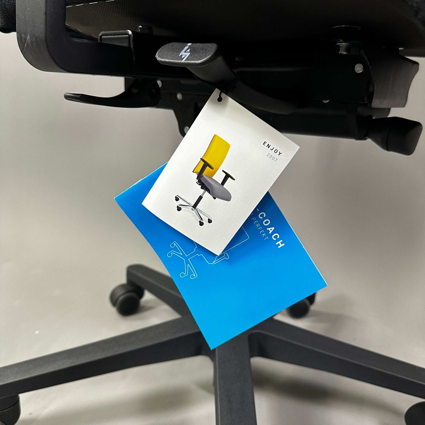 Westaro Enjoy ergonomic office chair tag hanging on black chair base with wheels