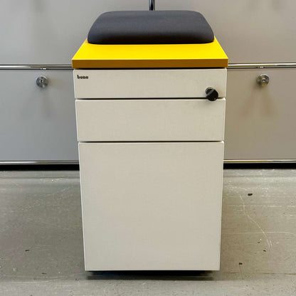 Rollcontainer CT senfgelb with white front, mustard yellow body, anthracite seat cushion, three drawers, lock, and hard caster wheels