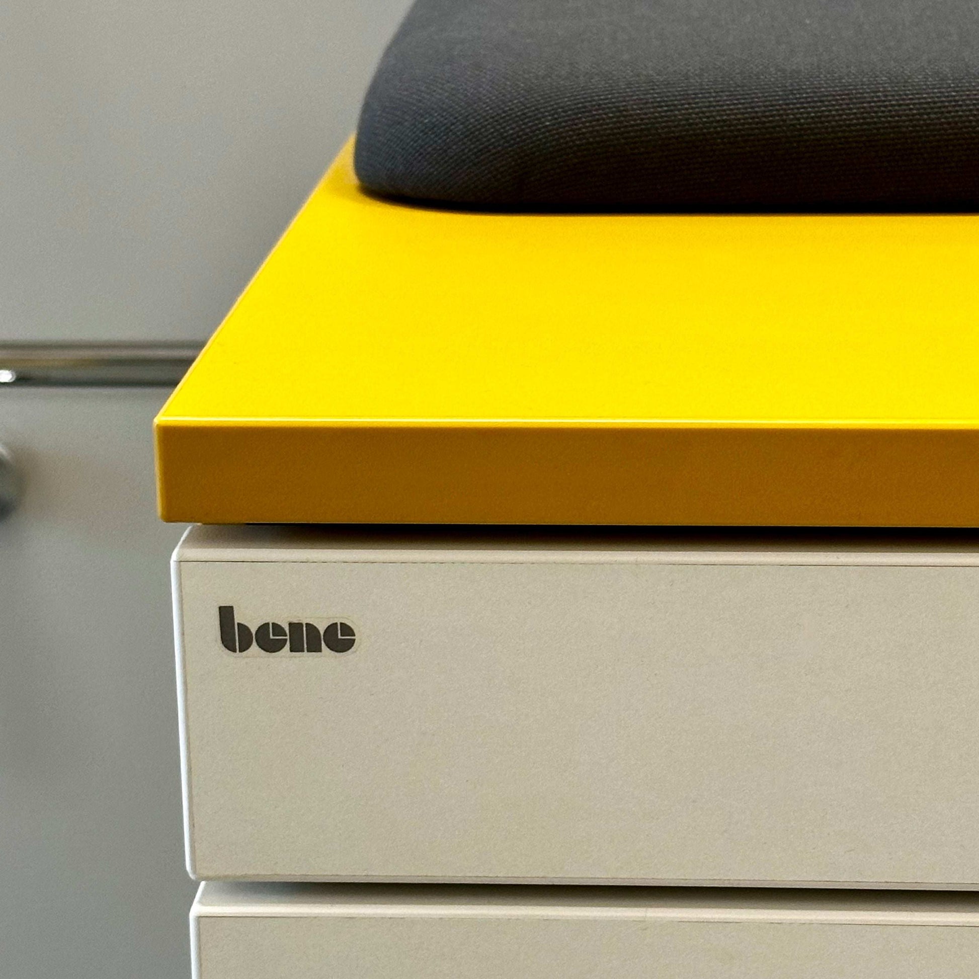 Close-up of Bene Rollcontainer CT in mustard yellow with white melamine front and anthracite fabric seat cushion