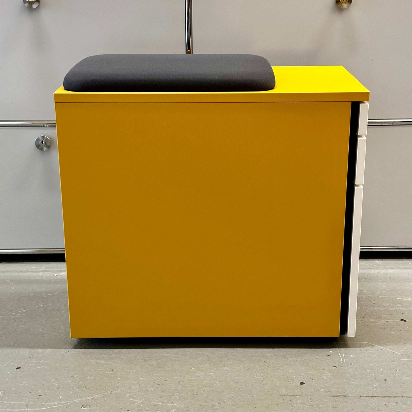 Yellow melamine Rollcontainer CT with white front, three drawers, anthracite fabric seat cushion, hard wheels, and safety support wheel.