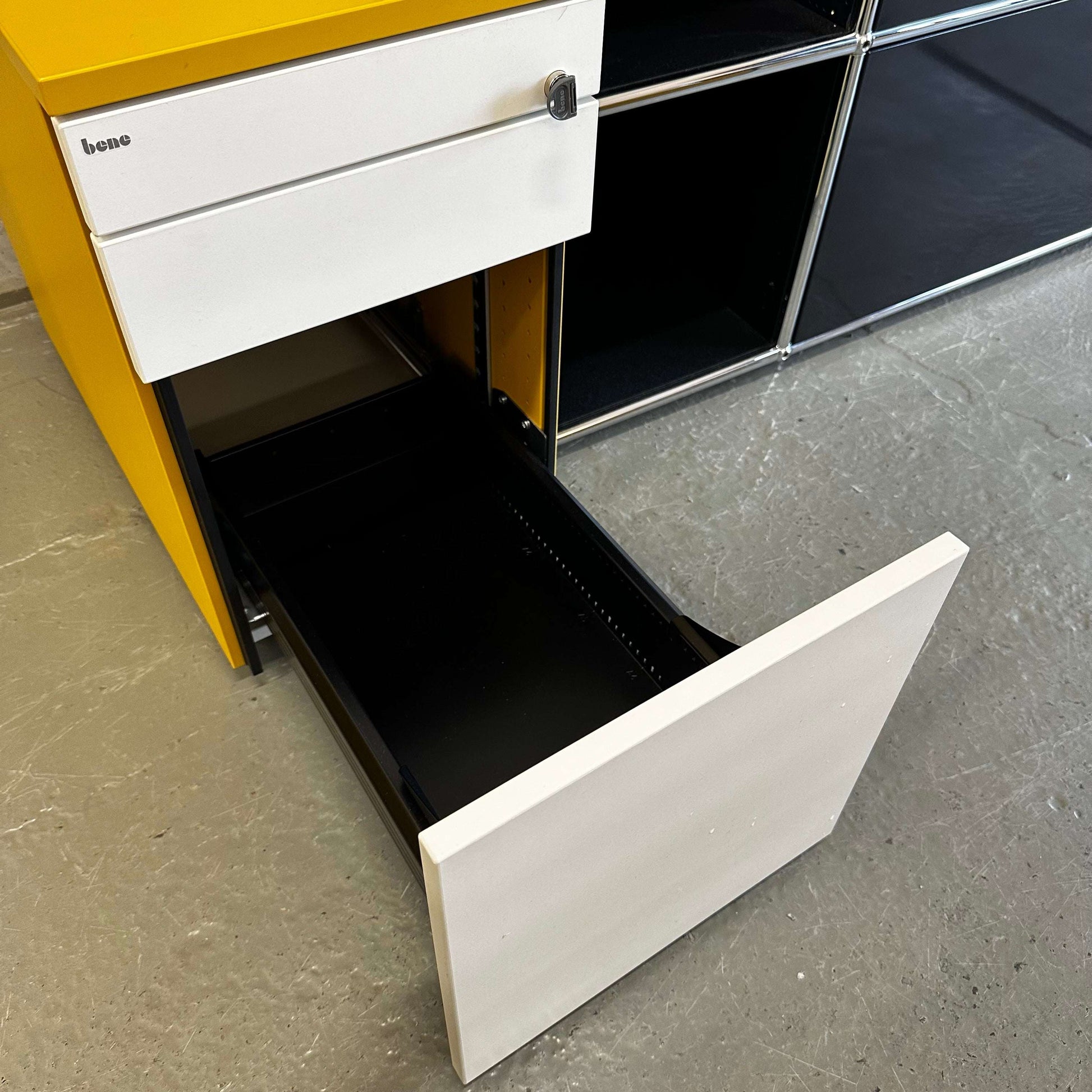 Bene Rollcontainer CT in mustard yellow with white melamine drawers, anthracite fabric seat cushion, three drawers with soft-close and lock, hard caster wheels, and support roller for stability.