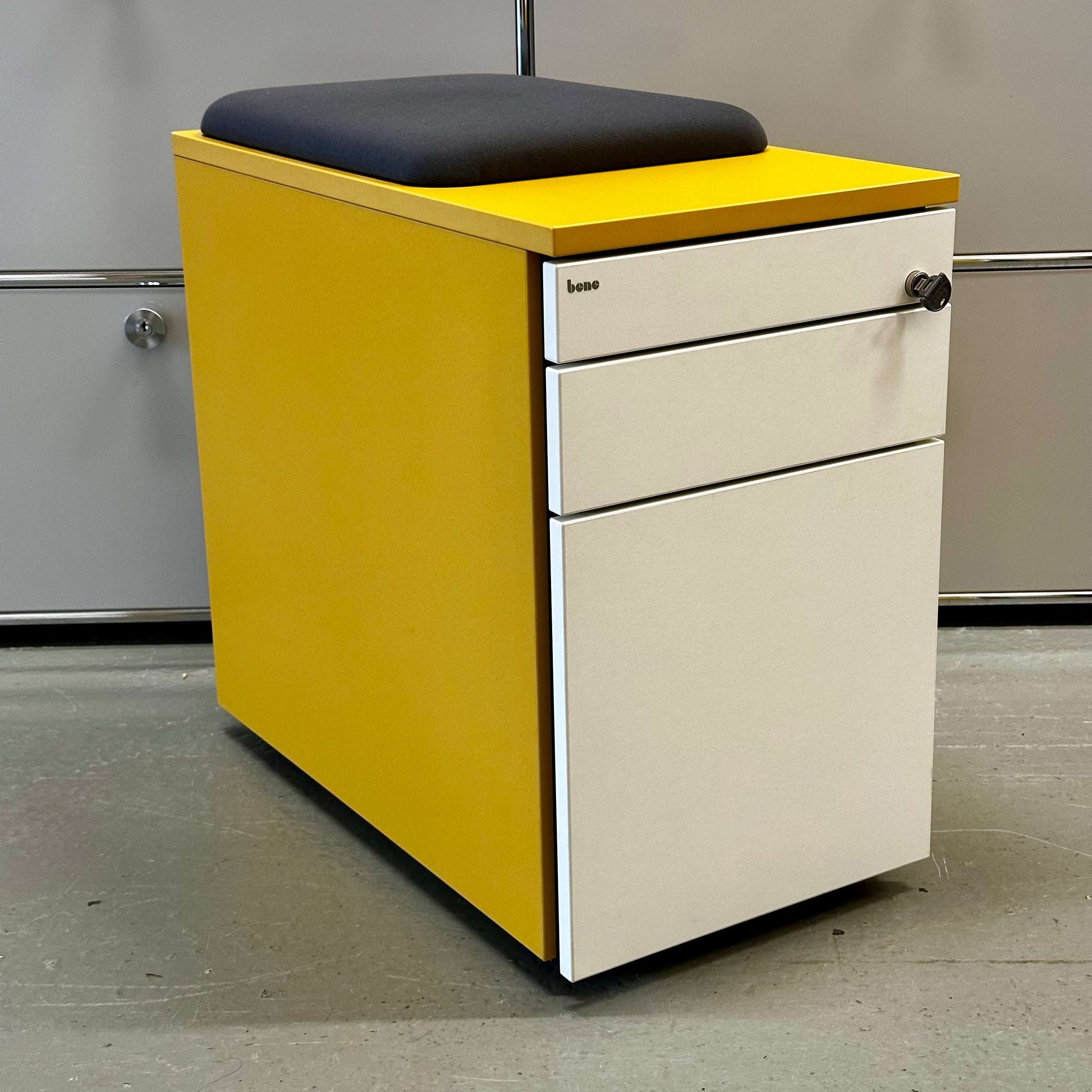Rollcontainer CT in senfgelb with white melamine front, three drawers, anthrazit fabric seat cushion, and lock