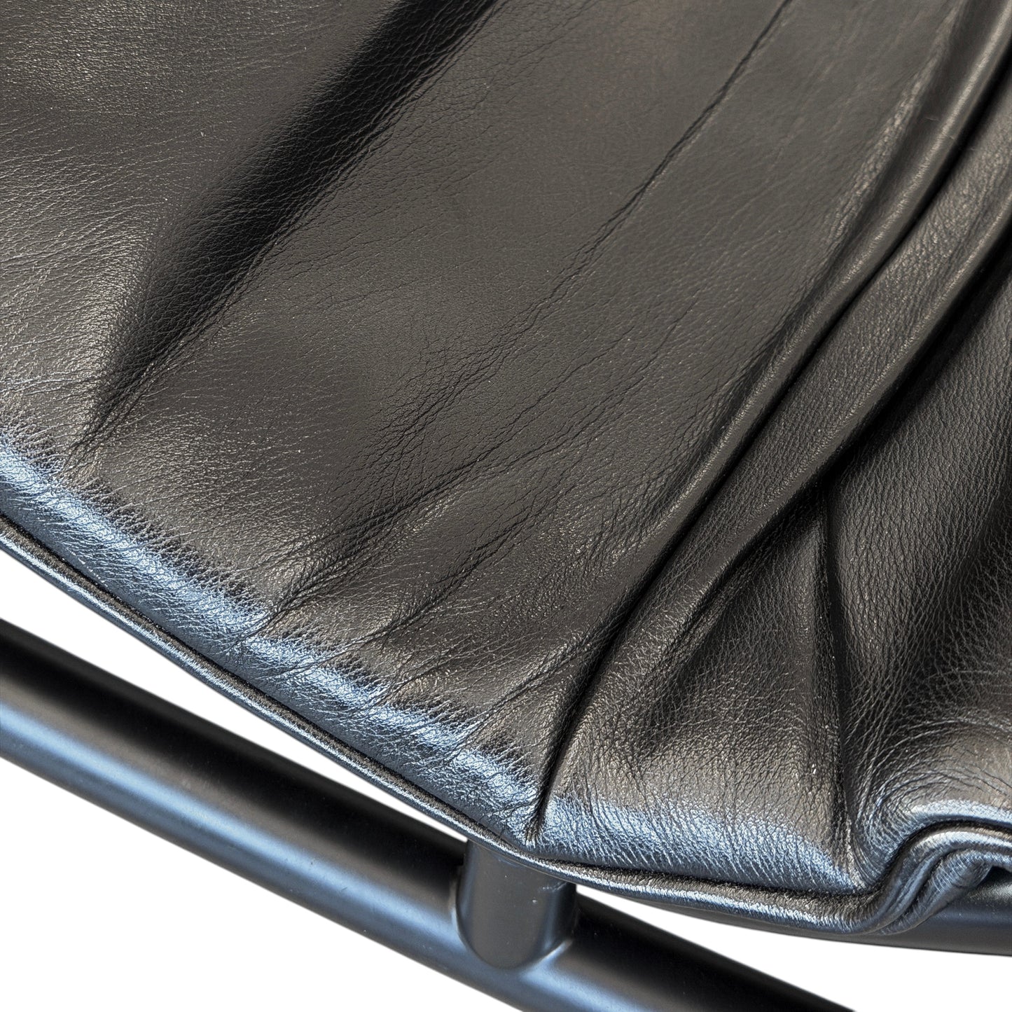Nahaufnahme der Cassina LC4 Liege aus schwarzem Leder mit sichtbarer Textur und Metallrahmen.