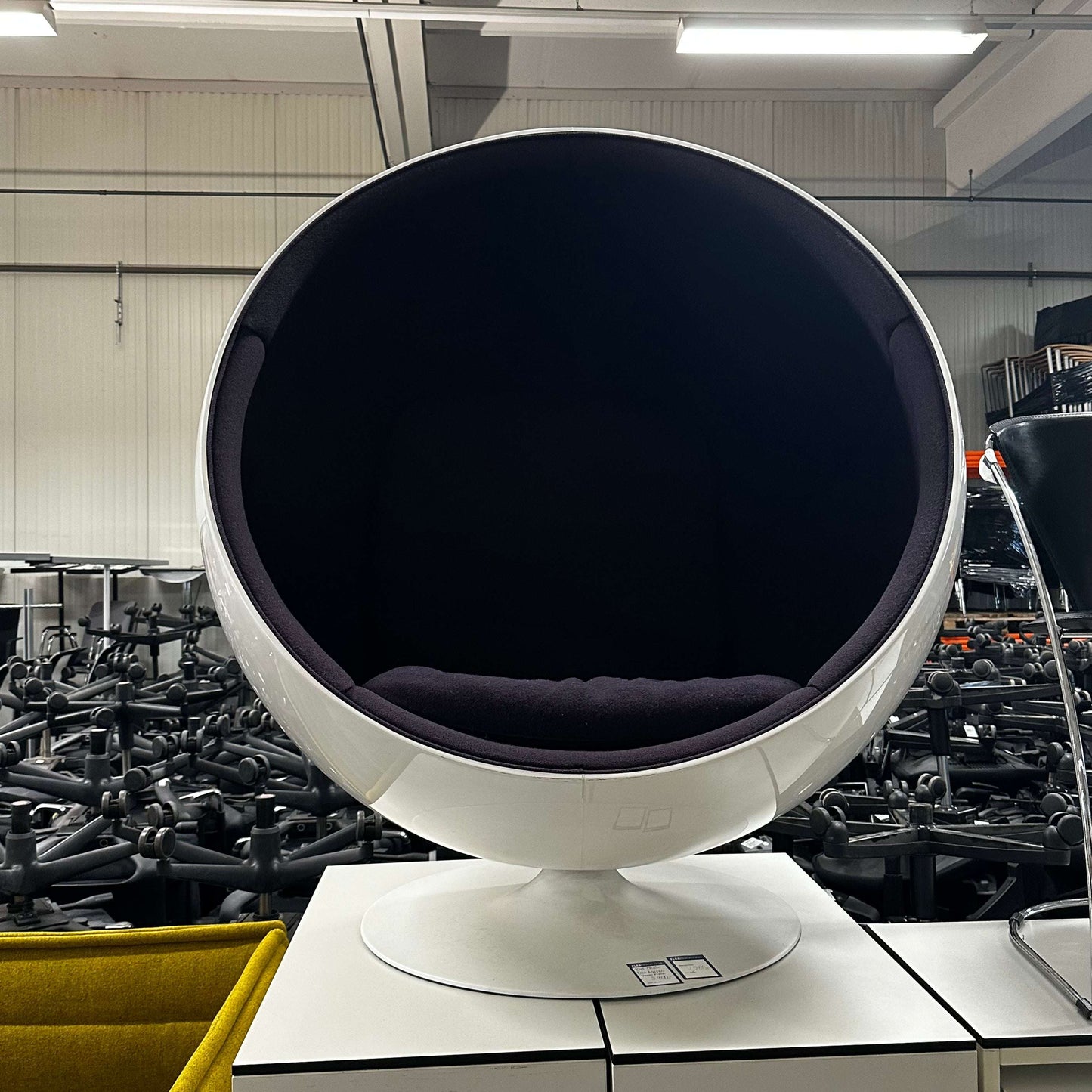 White Eero Aarnio Ball Chair with spherical design and black interior cushion in modern setting