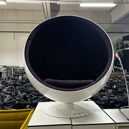 White Eero Aarnio Ball Chair with spherical design and black interior cushion in modern setting