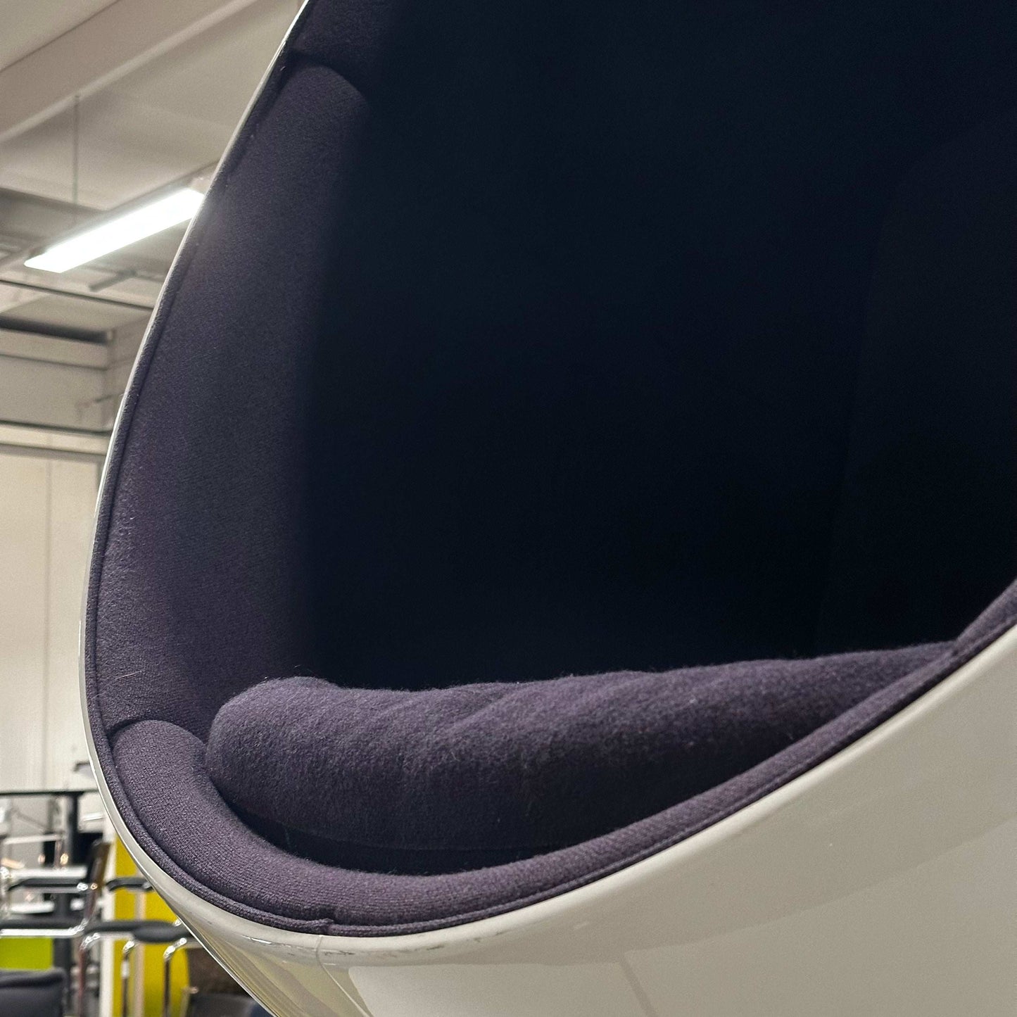 Close-up of white Eero Aarnio Ball Chair with black cushioned interior in modern setting