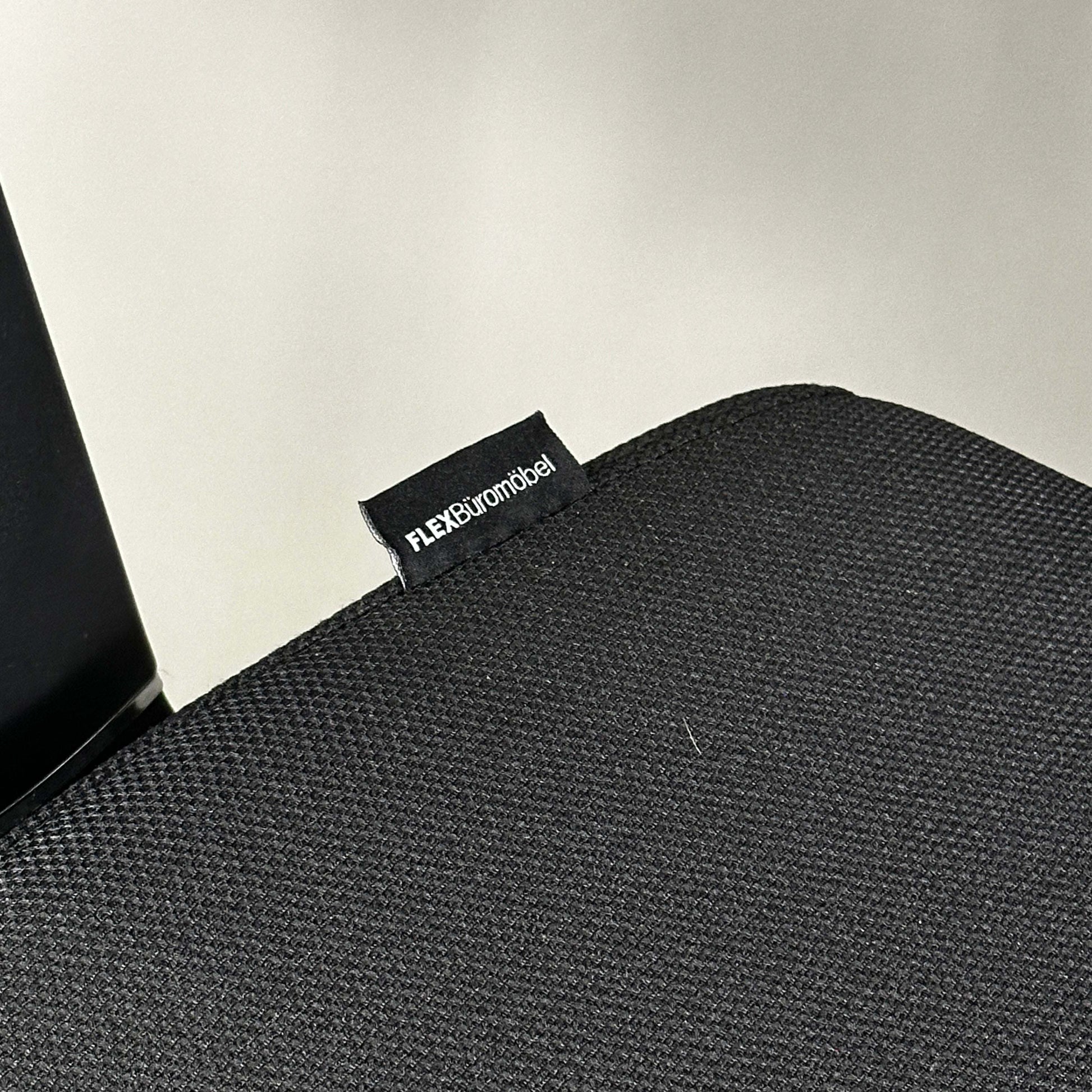 Close-up of black fabric seat with FLEX Büromöbel tag on ergonomic Ergo1 schwarz office chair