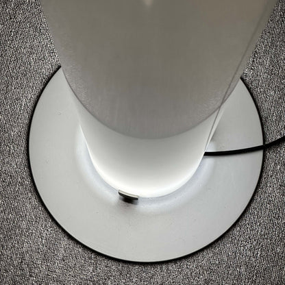 FLOS Stylos Stehlampe modern floor lamp with sleek white base and diffused lighting on textured carpet
