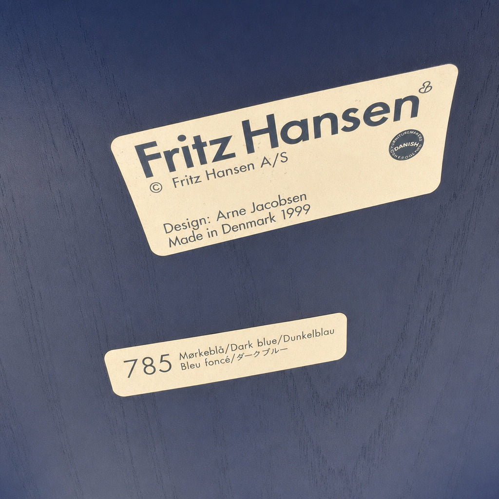 Blauer Fritz Hansen Serie 7 Stuhl mit Arne Jacobsen Herstellerschild und Holzmaserung auf der Sitzschale.