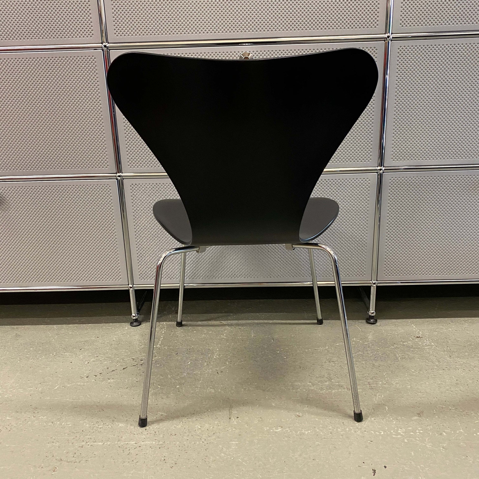 Black Fritz Hansen Serie 7 stackable chair with wooden seat and chrome legs viewed from the back