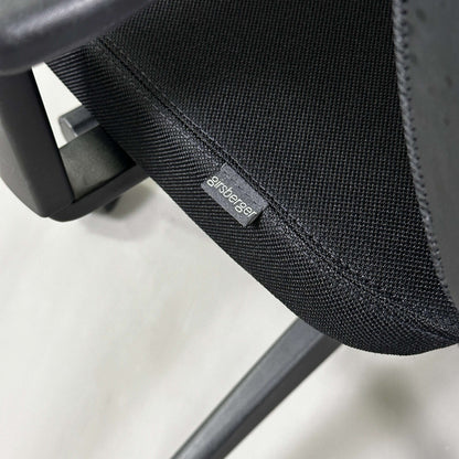 Close-up of black Girsberger Reflex office chair seat with fabric upholstery and mesh backrest showing brand label