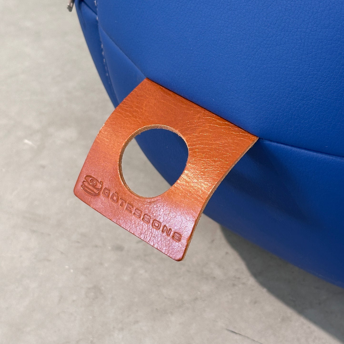 Götesons Office Ballz Sitzball aus blauem Kunstleder mit braunem Ledergriff und Logo.