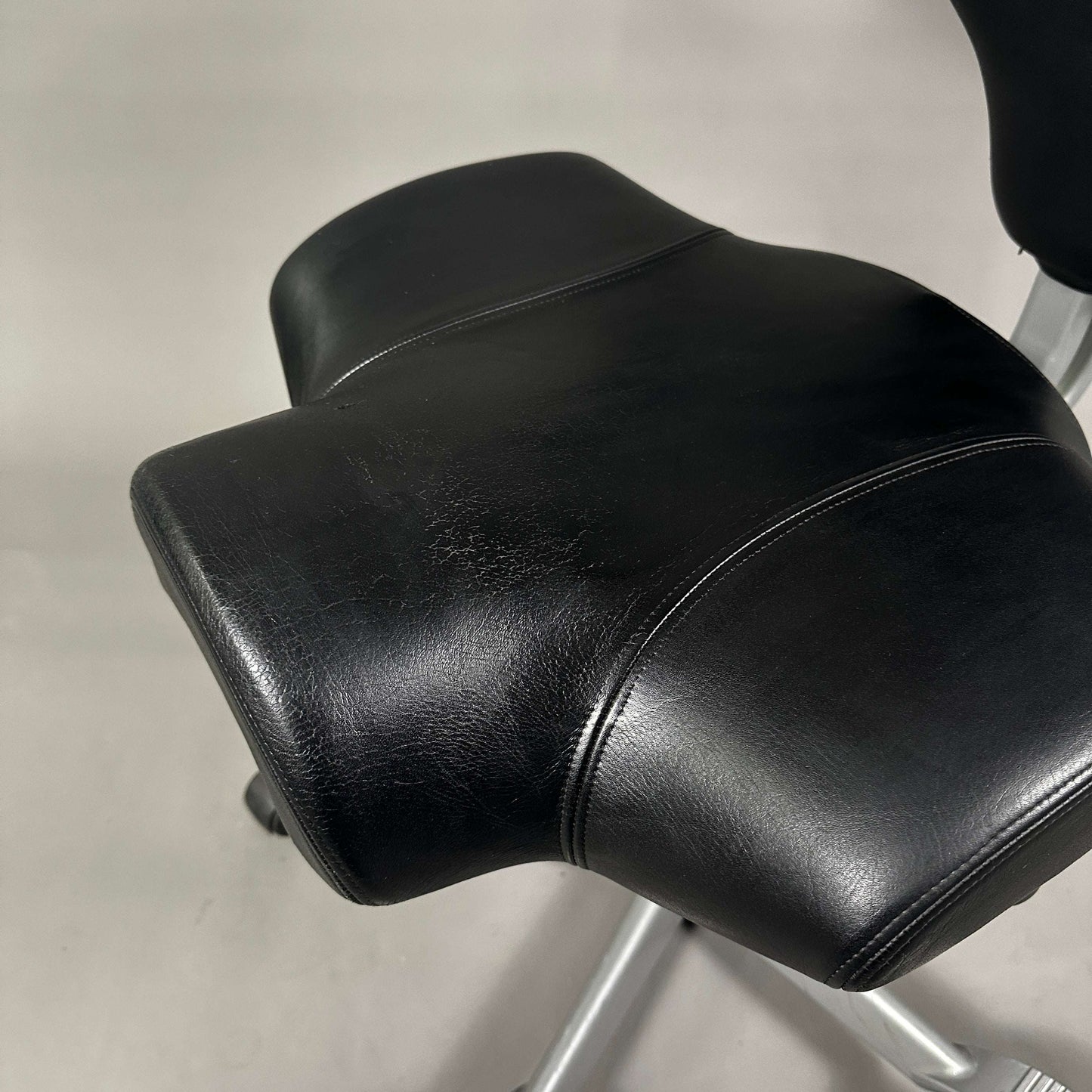 HAG Capisco 8106 Schreibtischstuhl mit schwarzem Softleder und poliertem Aluminiumgestell, sichtbare Abnutzung auf der Sitzfläche