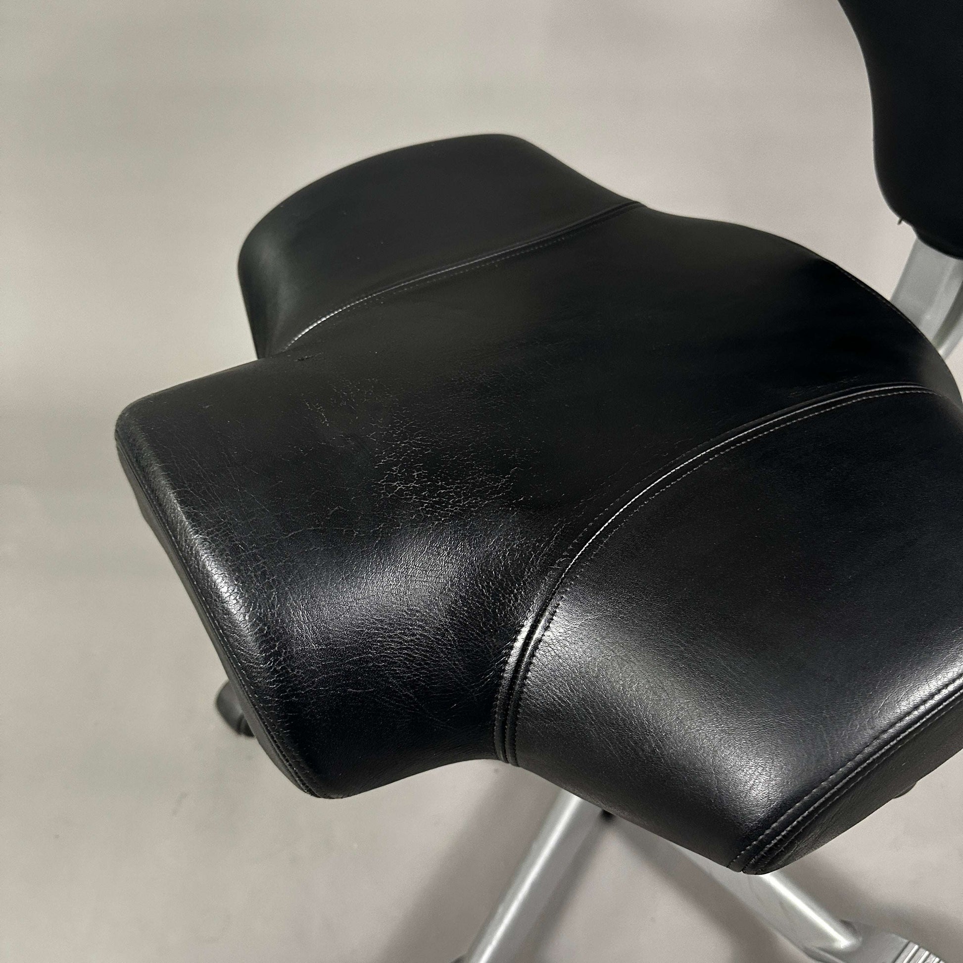 HAG Capisco 8106 Schreibtischstuhl mit schwarzem Softleder und poliertem Aluminiumgestell, sichtbare Abnutzung auf der Sitzfläche