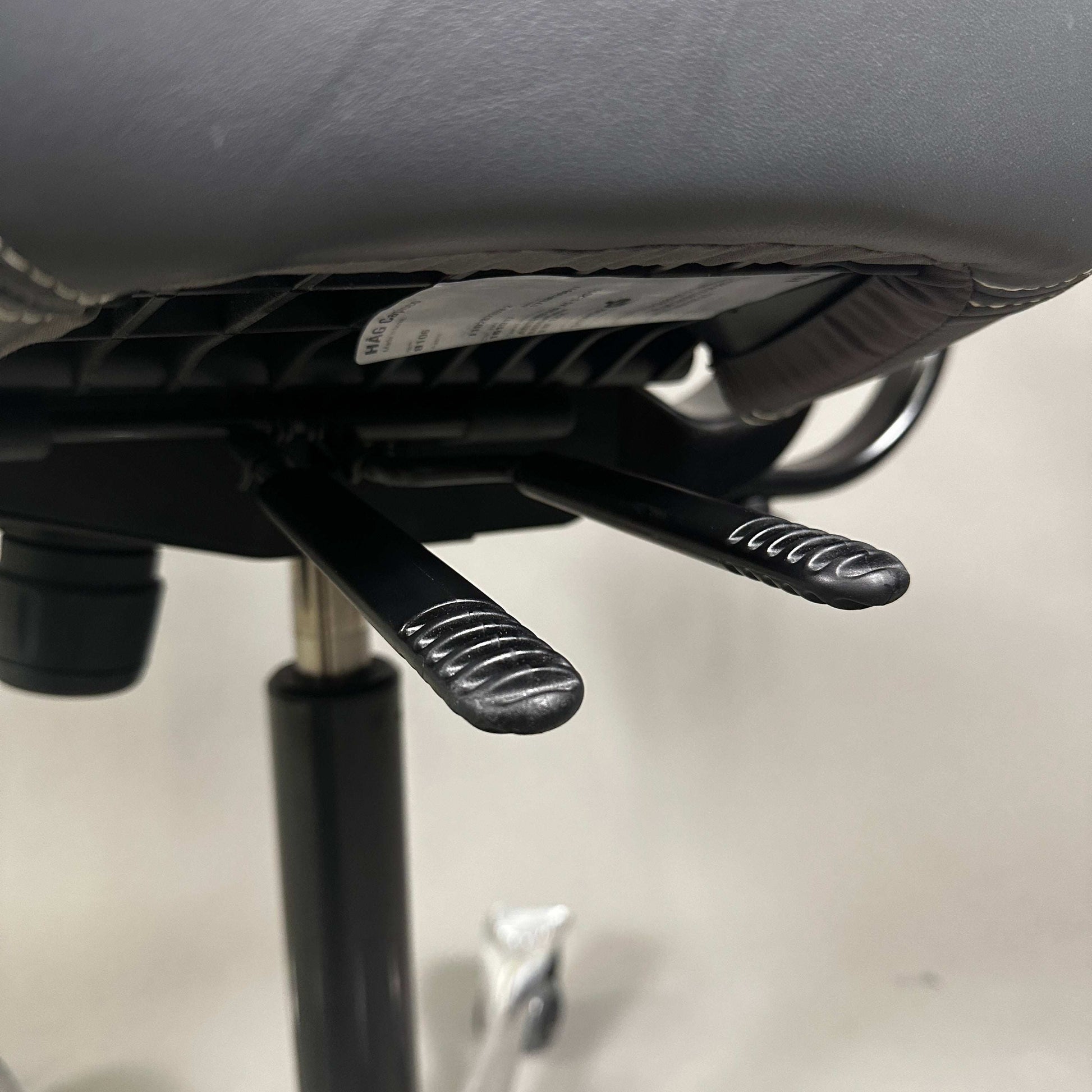 Detailaufnahme der Hebel des HAG Capisco 8107 Schreibtischstuhls mit grauem Soft Leder und poliertem Aluminiumgestell