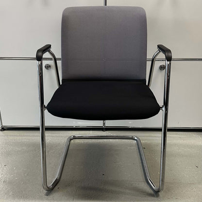 Haworth Comforto 29 visitor chair with ergonomic seat, black cushion, gray mesh backrest, and chrome cantilever frame for office or conference room seating