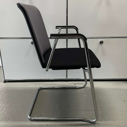Side view of a Haworth Comforto 29 visitor chair with black ergonomic seat and chrome cantilever frame