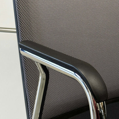 Close-up of Haworth Comforto 29 visitor chair armrest with chrome frame and black padding