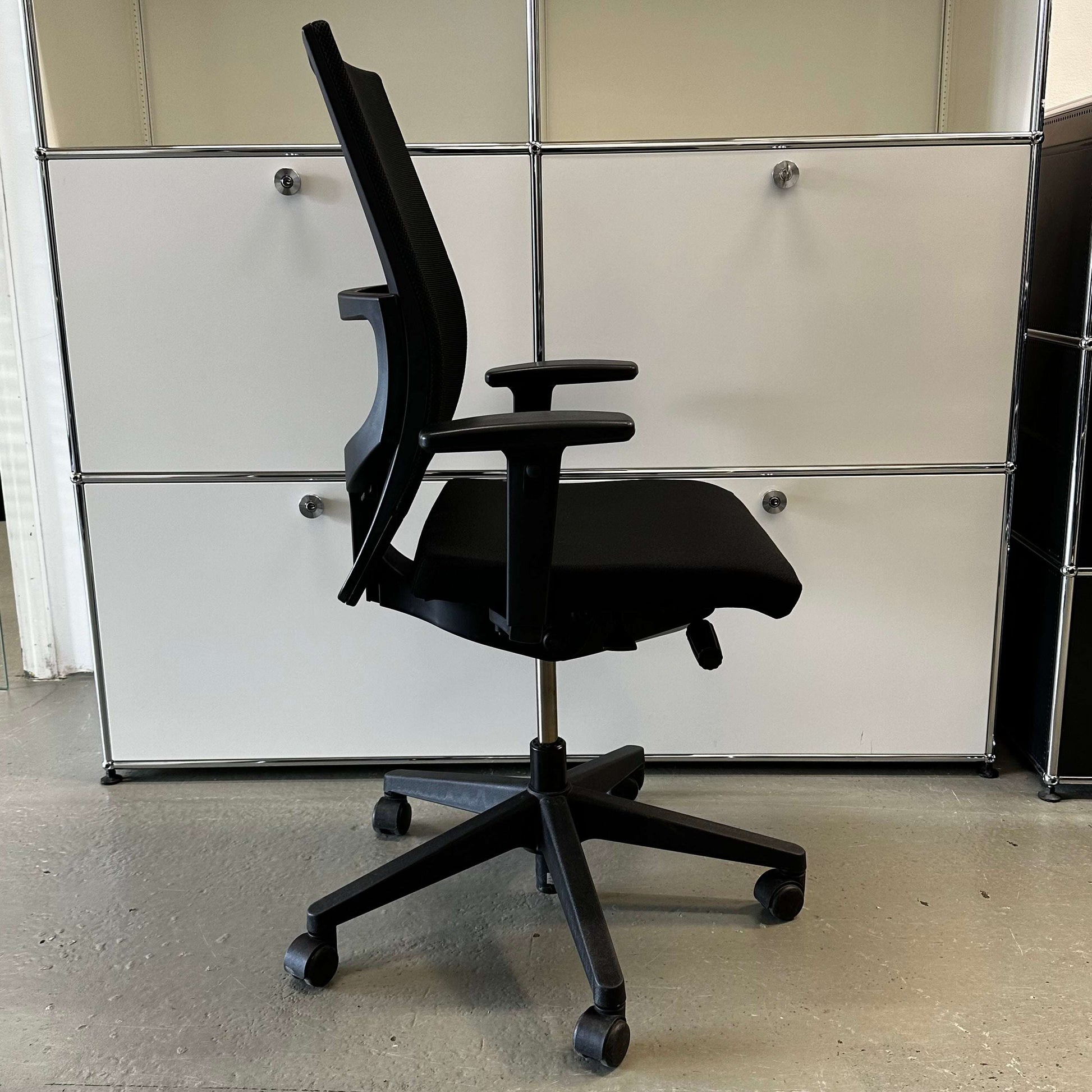 Haworth Comforto 39 black office chair with mesh back, adjustable armrests, height-adjustable seat, and black base with caster wheels